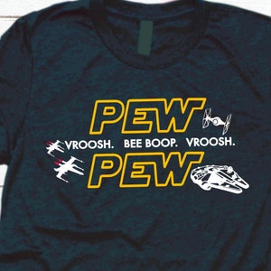May include: A dark blue t-shirt with a yellow graphic design that says "PEW PEW VROOSH. BEE BOOP. VROOSH." The graphic also includes a spaceship and a starfighter.