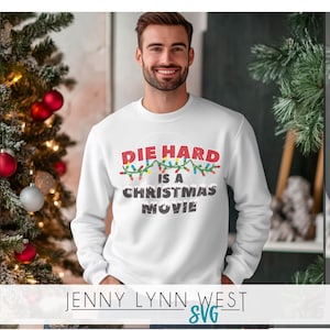 May include: White sweatshirt with a red, green, and blue graphic that says "Die Hard is a Christmas Movie" with Christmas lights around the text.