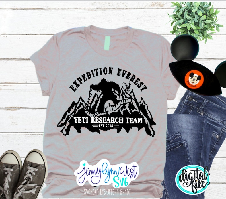 Pu&ograve; includere: Una maglietta grigia con un design grafico nero di uno yeti che scala una montagna con il testo "Expedition Everest Yeti Research Team Est. 2006"
