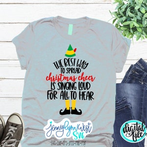 Puede incluir: Una camiseta azul claro con un dise&ntilde;o de elfo de Navidad y el texto "The best way to spread Christmas cheer is singing loud for all to hear".