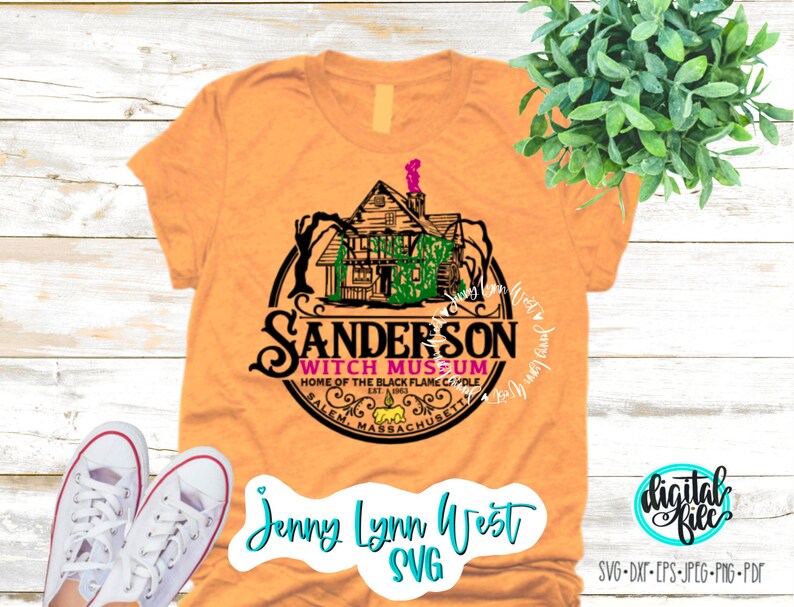 May include: A tan t-shirt with a black and white graphic of a house with a witch hat on top. The graphic is in a circle with the text "Sanderson Witch Museum" and "Home of the Black Flame Candle" inside. The text "Salem, Massachusetts" is at the bottom of the circle.