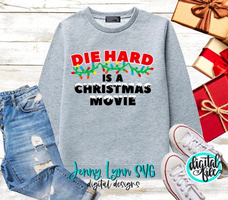 May include: Gray sweatshirt with the text "Die Hard is a Christmas Movie" in black letters with a string of colorful Christmas lights above the text.