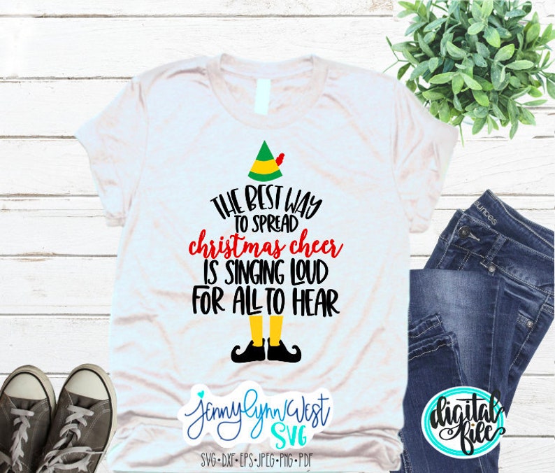 Puede incluir: Camiseta blanca con un gr&aacute;fico de elfo negro y verde y el texto "THE BEST WAY TO SPREAD christmas cheer IS SINGING LOUD FOR ALL TO HEAR".