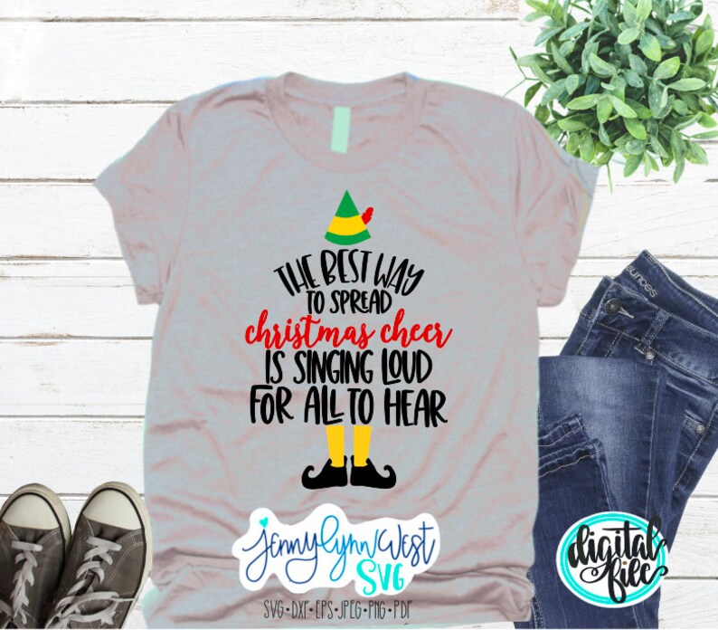 Puede incluir: Una camiseta gris con un gorro de elfo verde y el texto "THE BEST WAY TO SPREAD christmas cheer IS SINGING LOUD FOR ALL TO HEAR". El texto est&aacute; en negro y rojo. El gorro de elfo tiene un pomp&oacute;n rojo. El elfo lleva zapatos negros. El texto "Jenny Lynn West SVG" est&aacute; en la parte inferior de la camiseta. El texto "SVG-DXT-EPS-JPEG-PNG-PDF" est&aacute; debajo del nombre.