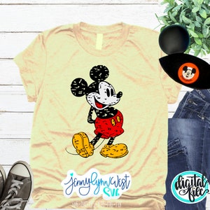 May include: A yellow t-shirt featuring a distressed black and white image of Mickey Mouse. Mickey is wearing his signature red shorts and yellow shoes. The text "JennyLynnWest SVG" is in the bottom left corner of the image.