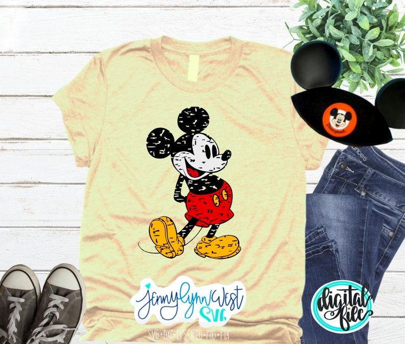 May include: A yellow t-shirt featuring a distressed black and white image of Mickey Mouse. Mickey is wearing his signature red shorts and yellow shoes. The text "JennyLynnWest SVG" is in the bottom left corner of the image.