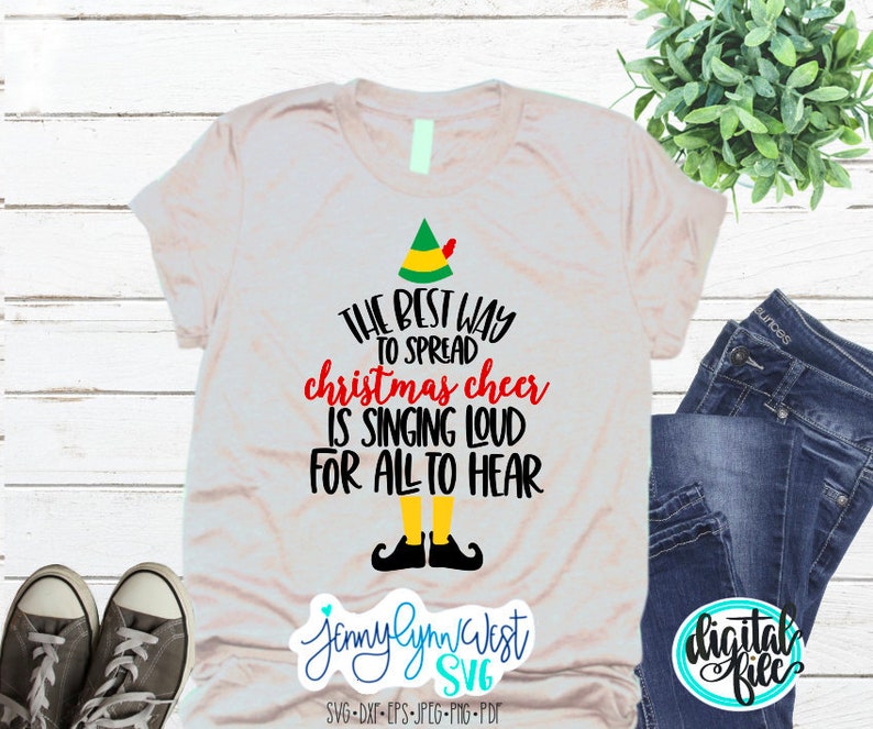 Puede incluir: Una camiseta beige con un gorro de elfo verde y el texto "THE BEST WAY TO SPREAD christmas cheer IS SINGING LOUD FOR ALL TO HEAR".