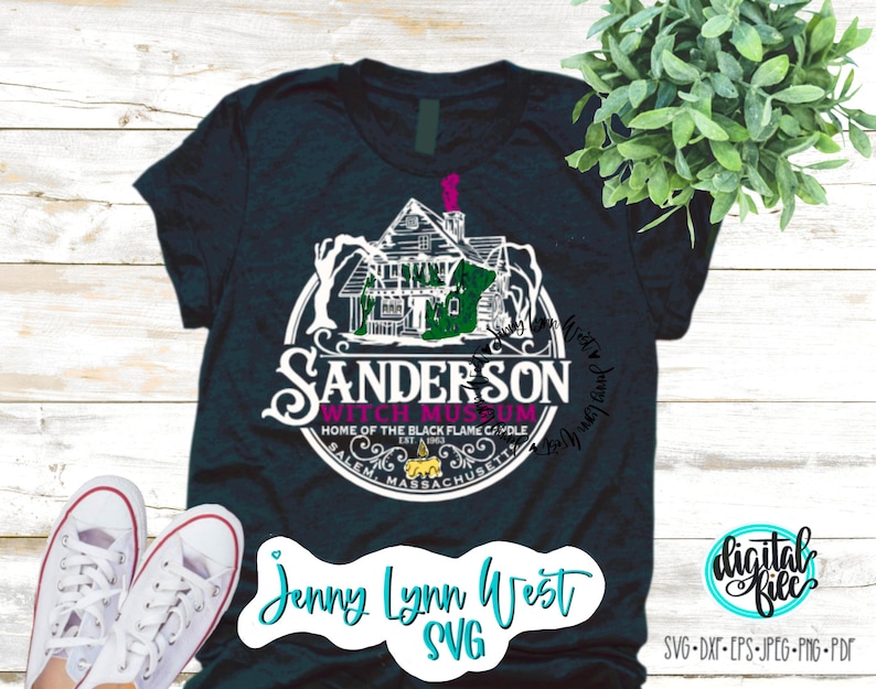 May include: A dark blue t-shirt with a white graphic of the Sanderson Witch Museum in Salem, Massachusetts. The graphic includes a black and white illustration of the museum building, a witch's hat, and the text "Sanderson Witch Museum, Home of the Black Flame Candle, Est. 1963, Salem, Massachusetts". The t-shirt also has the text "Jenny Lynn West SVG" in white.