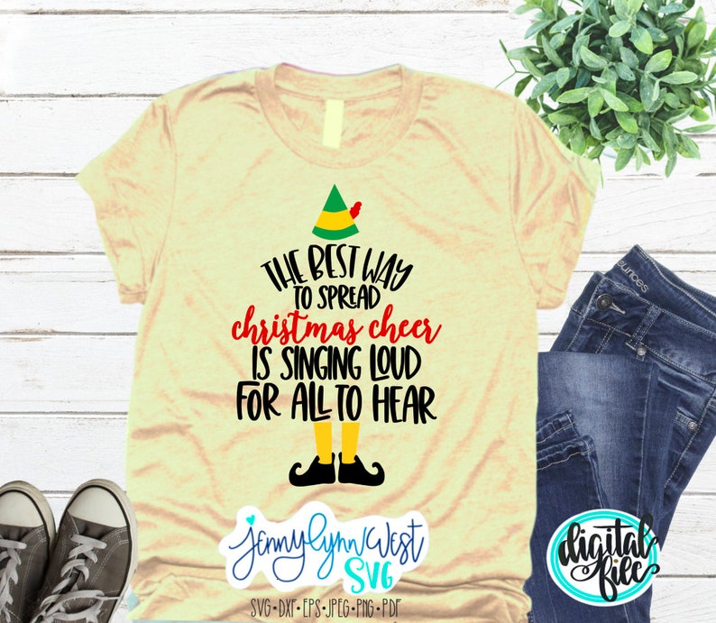 Puede incluir: Una camiseta amarilla con un gorro de elfo verde y el texto "THE BEST WAY TO SPREAD christmas cheer IS SINGING LOUD FOR ALL TO HEAR".