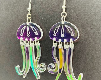 May include: A pair of iridescent purple and green jellyfish dangle earrings. The earrings are made of clear acrylic and have a silver hook.
