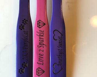May include: Three wooden sticks painted in purple and pink with different designs and text engraved on them. The text on the sticks reads "AKA Purplecat", "Love 2 Sparkle", and "Amethyst Sunset".