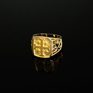 Op de afbeelding: Een gouden ring met een reli&euml;f van een kruis. Het kruis is omgeven door een decoratieve rand.