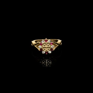 May include: A gold ring with a cross design and red and white gemstones.