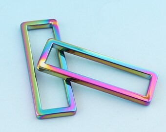 May include: Two iridescent metal rectangular frames, one on top of the other. The frames are hollow and have a smooth, shiny finish.