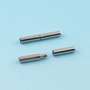 Può includere: Due tubi di metallo argentato, uno è diviso in due pezzi, l'altro è intero. I tubi sono lunghi circa 2,5 cm.