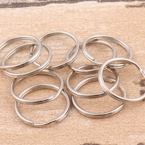 Könnte beinhalten: Ein Satz mit zehn silbernen Schlüsselringen. Die Ringe sind alle gleich groß und aus Metall.