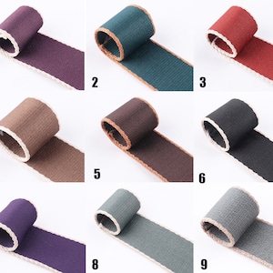 May include: Nine different colors of woven cotton webbing with a white trim. The webbing is approximately 1 inch wide.