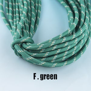May include: A close-up of green paracord with a white and tan stripe pattern. The paracord is coiled and tied in a knot. The text "F. green" is visible below the paracord.