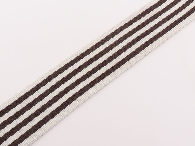 May include: White and brown striped webbing with a woven texture.