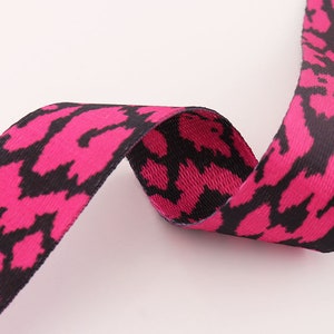 May include: Pink and black patterned ribbon with a woven texture.