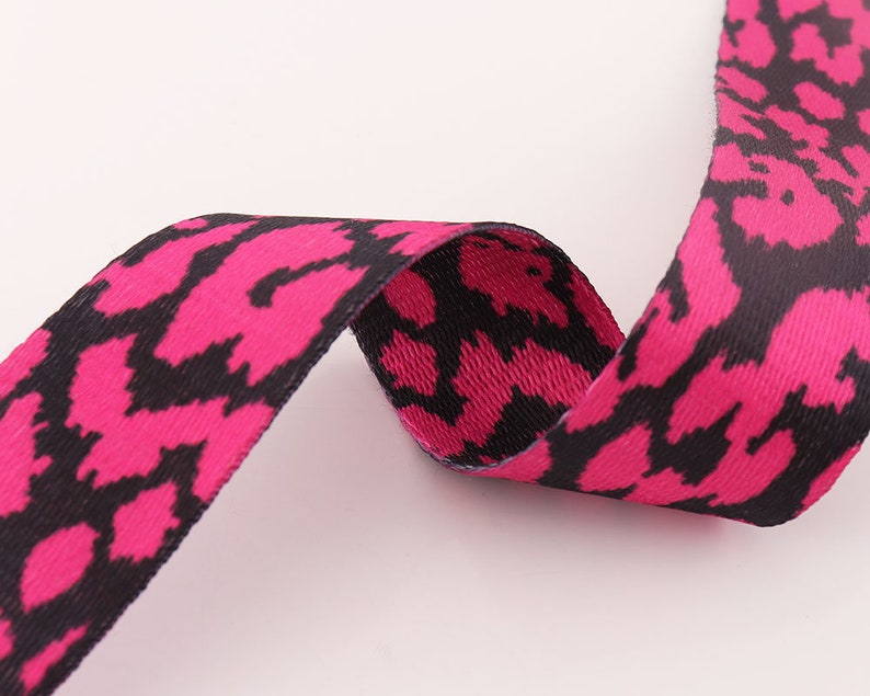 May include: Pink and black patterned ribbon with a woven texture.