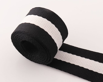 May include: Black and white striped webbing ribbon. The ribbon is rolled up and the white stripe is visible on the top.