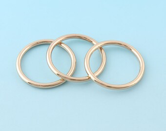 May include: Three gold-colored metal rings interlocked together. The rings are smooth and round.