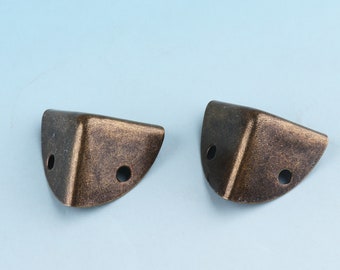 May include: Two antique gold corner protectors with a distressed finish. The protectors have two holes each for attaching to furniture.
