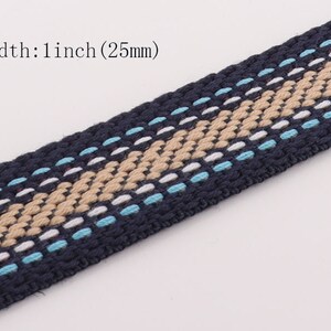 Pode incluir: Um close-up de uma fita tecida azul e bege com um padrão branco e azul claro. A fita tem 1 polegada (25 mm) de largura.