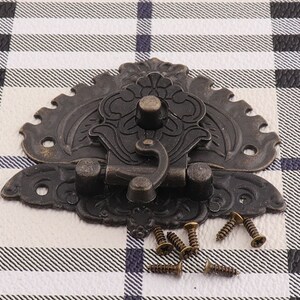 May include: Antique-style ornate metal latch with a decorative floral design. The latch is black and has a hook-shaped closure. It comes with screws for installation.