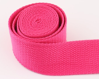 May include: A bright pink cotton webbing strap rolled up. The strap is woven with a textured pattern.