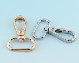 May include: Two metal swivel clasps, one gold and one silver. The clasps are used for attaching straps or chains to bags, purses, or other items.
