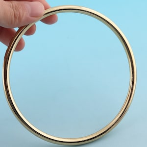 Peut inclure: Un anneau ou un cercle en métal de couleur dorée, avec une finition lisse et polie.