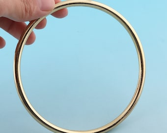 Op de afbeelding: Een gouden metalen ring of hoepel met een gladde, gepolijste afwerking.