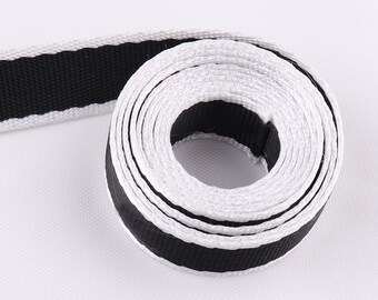 May include: A roll of black and white striped ribbon. The ribbon is made of a woven fabric and has a smooth texture.