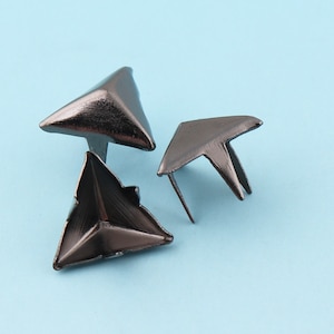 May include: Three black metal triangle-shaped corner protectors. The protectors have a pointed tip and a flat base.
