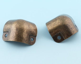 May include: Two antique gold corner protectors with a distressed finish. Each protector has two holes for attaching to furniture.