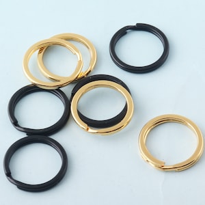 Puede incluir: Surtido de llaveros de metal dorado y negro. Los llaveros son todos circulares y tienen un diseño sencillo.