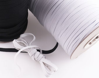May include: Two spools of elastic cord, one black and one white, with a length of white elastic cord lying on a white surface.