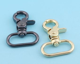 May include: Two metal swivel clasps, one black and one gold, with a rounded oval loop. These clasps are commonly used for attaching straps or chains to bags, purses, or other accessories.