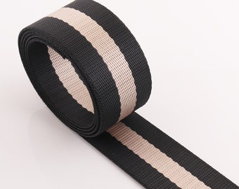 May include: Black and beige striped webbing, a type of woven fabric used for straps, belts, and other applications.