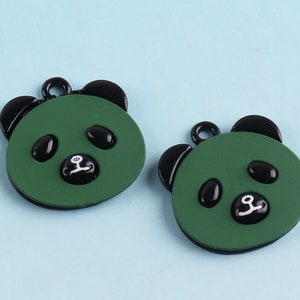 May include: Two green panda bear charms with black ears and eyes. The charms have a white nose and mouth.