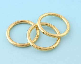 May include: Three gold-colored metal rings, interlocked, on a light blue background.