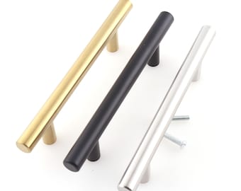 Può includere: Tre maniglie per armadi in diverse finiture: oro, nero e argento. Ogni maniglia è una barra lunga e dritta con estremità arrotondate.
