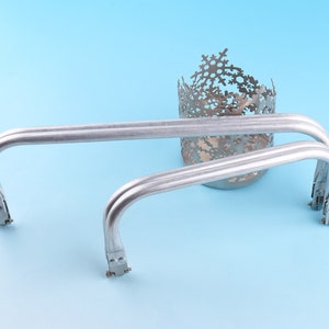 May include: Two silver metal handles with a snowflake design. The handles are curved and have a smooth finish.