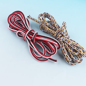 May include: Two spools of colorful rope. One spool is red, white, and black. The other spool is yellow, blue, and brown.