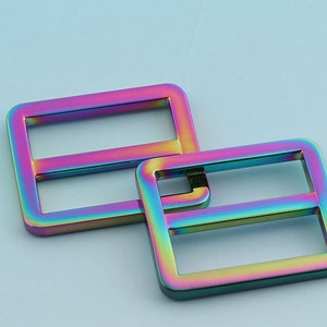 May include: Two iridescent metal slider buckles, one larger than the other, with a rainbow finish. The buckles are made of metal and have a smooth, polished surface.