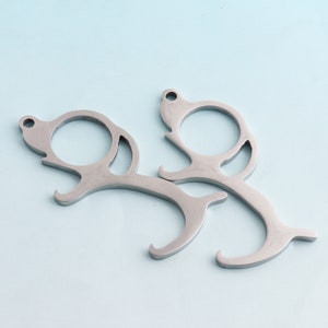 May include: Two silver-toned door openers with a hook and loop design. The openers are designed to help people avoid touching surfaces in public places.