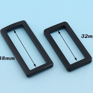 May include: Two black metal belt buckle slides, one measuring 38mm by 32mm and the other measuring 32mm by 32mm.