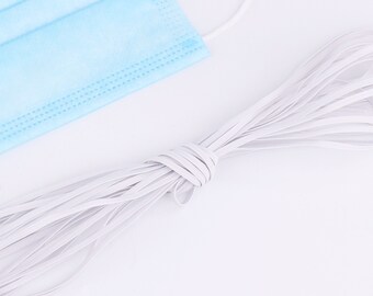 May include: A close-up of a white elastic cord, commonly used for face masks. The cord is coiled and ready for use.